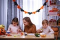 Happy woman with her daughter and son getting ready for Halloween. The family sits at the table, the mother helps the Royalty Free Stock Photo