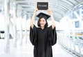 Happy woman on her graduation day holding board on above of head