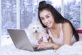 Happy woman and her puppy using laptop on bed Royalty Free Stock Photo