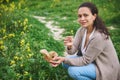 Happy smiling woman looking at camera while picking medicinal herbs in the meadow. Aromatherapy or preparing herbal tea