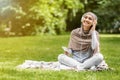 Happy woman in hijab enjoying music while resting at park Royalty Free Stock Photo