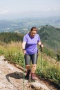 Happy woman hiker with backpack standing on the slope of mountain ridge against mountains. 30s Women holding hiking Royalty Free Stock Photo