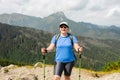 Happy woman hiker with backpack standing on the slope of mountain ridge against mountains. 30s Women holding hiking Royalty Free Stock Photo