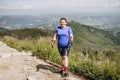 Happy woman hiker with backpack standing on the slope of mountain ridge against mountains. 30s Women holding hiking Royalty Free Stock Photo