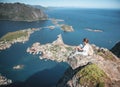 Happy woman hiker enjoying scenic view at the top of Reinebringen hike above Reine village in the Lofoten archipelago, travel to