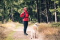 Happy woman hiking with dog in woods Royalty Free Stock Photo