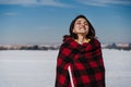 happy woman hiking outdoors in snowy mountain. Wrapped in plaid blanket. Nature and lifestyle