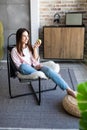 Happy woman holding an apple and a glass of water sitting on a sofa in the living room Royalty Free Stock Photo