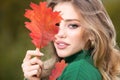 Happy woman holding autumn leafs on face in fall nature. Portrait of young woman with autumn maple leaves outdoor Royalty Free Stock Photo