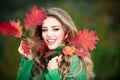 Happy woman holding autumn leafs on face in fall nature. Portrait of young woman with autumn maple leaves outdoor Royalty Free Stock Photo