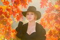 Happy woman holding autumn leafs on face in fall nature. Portrait of young woman with autumn maple leaves outdoor Royalty Free Stock Photo