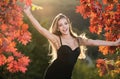 Happy woman holding autumn leafs on face in fall nature. Portrait of young woman with autumn maple leaves outdoor Royalty Free Stock Photo
