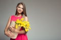 Young happy woman holding basket with yellow tulips. Gray background. Royalty Free Stock Photo