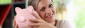 Happy woman holding big piggy bank in her hands and looking at camera close-up. Royalty Free Stock Photo