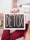 Happy woman holding board with detox sign