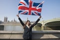 Happy woman holding British flag while standing against Big Ben at London, England, UK Royalty Free Stock Photo