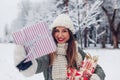 Happy woman holding Christmas presents gift boxes in snowy winter park offering one. Festive holiday season. Space Royalty Free Stock Photo