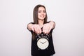 Happy woman holding clock against a grey Royalty Free Stock Photo