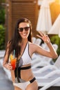 Happy woman holding a cocktail near deck chairs Royalty Free Stock Photo