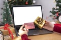 Happy woman holding credit card doing online shopping present at Christmas. Mockup laptop computer with white screen Royalty Free Stock Photo