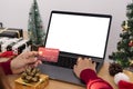 Happy woman holding credit card doing online shopping present at Christmas. Mockup laptop computer with white screen Royalty Free Stock Photo