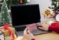 Happy woman holding credit card doing online shopping present at Christmas. Mockup laptop computer with white screen Royalty Free Stock Photo