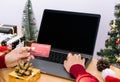 Happy woman holding credit card doing online shopping present at Christmas. Mockup laptop computer with white screen Royalty Free Stock Photo