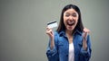 Happy woman holding credit card in hands, cash back services, grey background Royalty Free Stock Photo