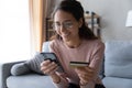 Happy woman holding credit card and smartphone make on-line purchase