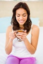 Happy woman holding cup of tea while sitting on bed Royalty Free Stock Photo