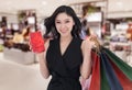 Happy woman holding gift box and shopping bag at mall Royalty Free Stock Photo