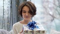 Happy woman holding gift boxes with Merry Christmas decoration in window background. Close up of woman holding gifts Royalty Free Stock Photo