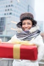 Happy woman holding gift during winter in city