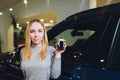 Happy woman holding keys to her new car at the dealership. Royalty Free Stock Photo