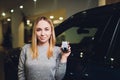 Happy woman holding keys to her new car at the dealership. Royalty Free Stock Photo