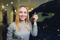 Happy woman holding keys to her new car at the dealership. Royalty Free Stock Photo