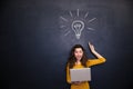 Happy woman holding laptop and having idea over blackboard background