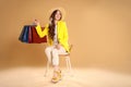 Happy woman holding many colorful shopping bags on armchair against beige background Royalty Free Stock Photo