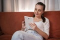 Happy woman holding pad computer gadget using digital tablet technology sitting on the couch at home. Smiling young Royalty Free Stock Photo