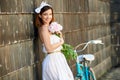 Happy woman holding peonies leaning against the wall and smiling Royalty Free Stock Photo