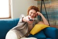 Happy woman holding remote control lying on cozy couch Royalty Free Stock Photo