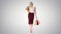 Happy woman holding shopping bags, smiling and walking on gradient background. Royalty Free Stock Photo