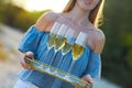 Happy woman holding tray with champagne sparkling wine into glasses outdoors at a beach Royalty Free Stock Photo