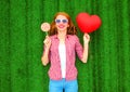 Happy woman holds a red air balloon in the shape of a heart, lollipop