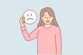 Happy woman holds sad emoticon calling to be optimist and have positive mood for achieve goals. Royalty Free Stock Photo