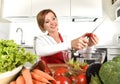 Happy woman at home kitchen preparing vegetable salad with lettuce, carrots and slicing tomato smiling Royalty Free Stock Photo