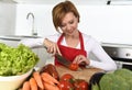 Happy woman at home kitchen preparing vegetable salad with lettuce carrots and slicing tomato Royalty Free Stock Photo