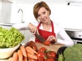 Happy woman at home kitchen preparing vegetable salad with lettuce carrots and slicing tomato Royalty Free Stock Photo