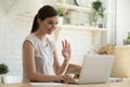 Young woman making video call on laptop and waving hand