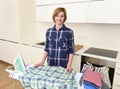 happy woman or housewife ironing shirt at home kitchen using iron and board smiling cheerful Royalty Free Stock Photo